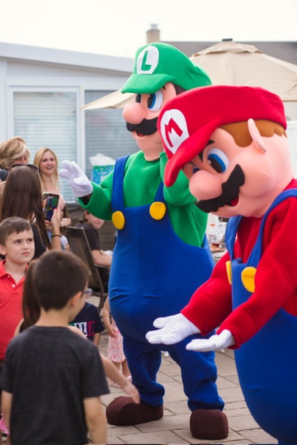 Mario and Luigi with kids at a party doing a low five | Rent Party Characters