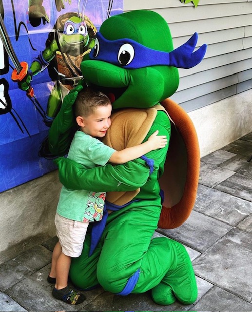 Teenage Mutant Ninja Turtles Leonardo hugging a child | Rent Party Characters